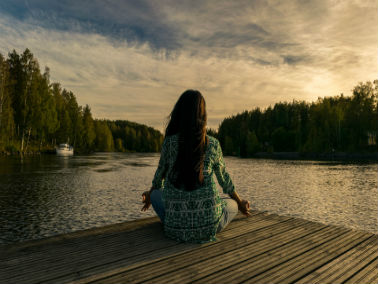 woman meditating by a lake