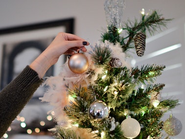 person reaching up to decorate tallest part of Christmas tree...