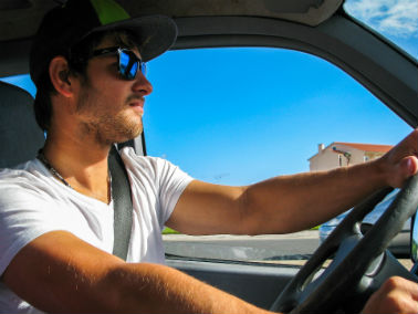Man wearing sunglasses and hat driving in summer