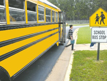 kid getting off the school bus in front of school zone sign