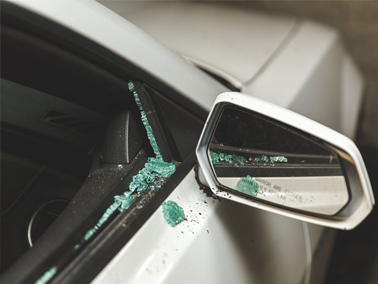 Left rear-view mirror and door of stolen white car. Door glass is broken.
