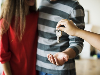 person handing over house keys to a couple