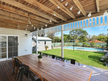 backyard wooden patio with pool in the background