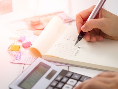 a person using a calculator with one hand and holding a pen in the other hand
