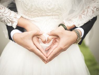bride and groom creating heart shape with their hands