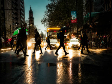pedestrians crossing holding umbrellas