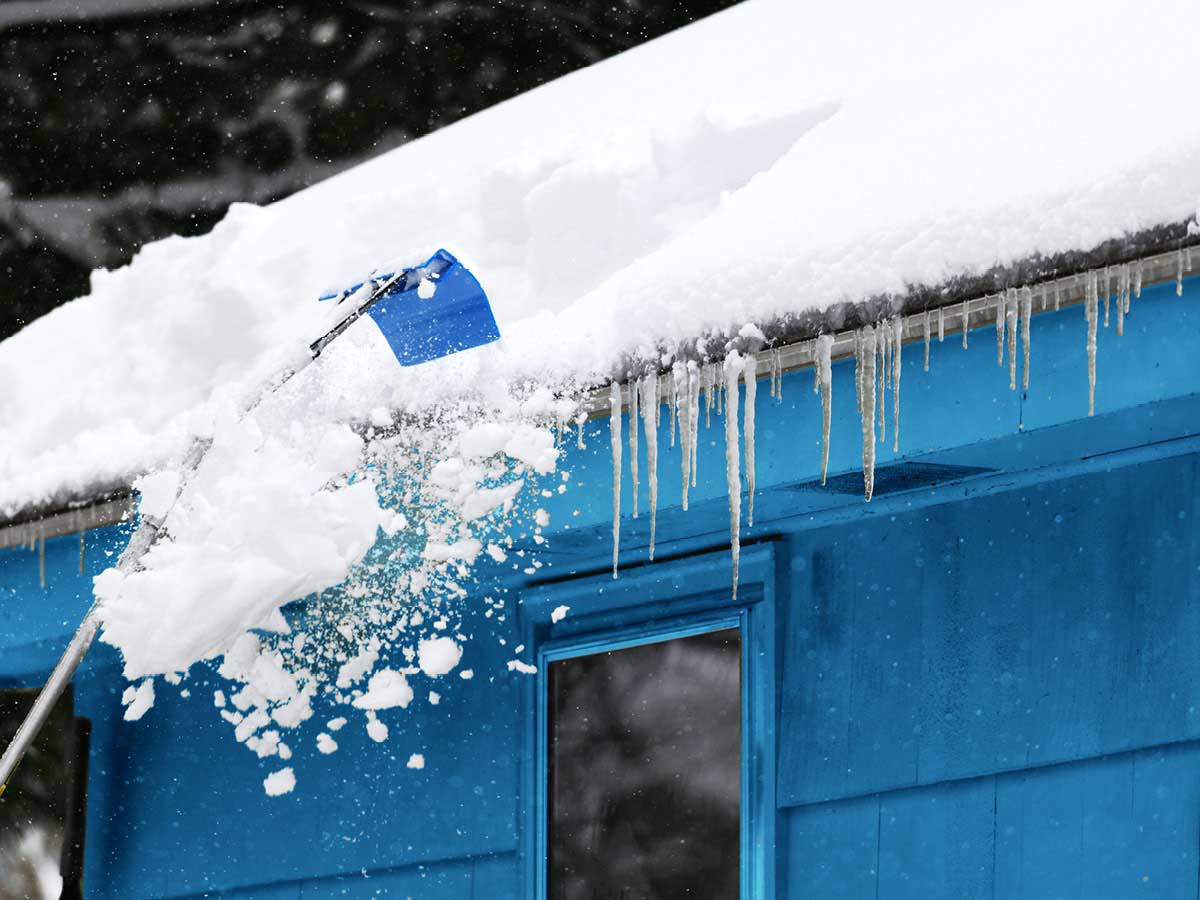 A snow-covered roof has icicles hanging from the eaves.